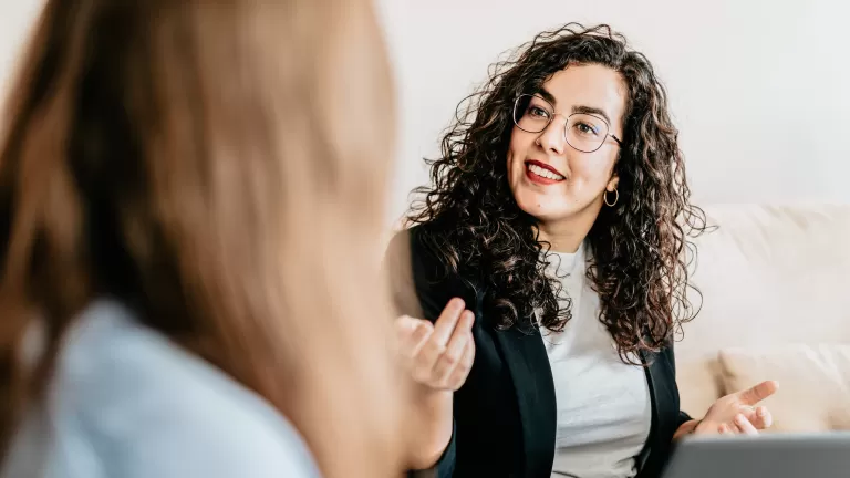 Frau mit Locken und Brille erklärt etwas